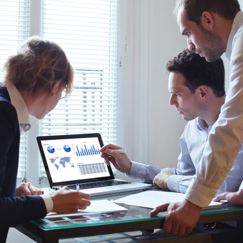 three coworkers looking graphs and data on a lap top